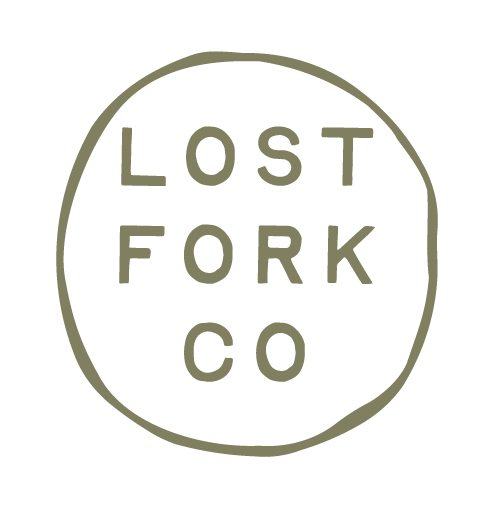 A hand-drawn circle with the words "LOST FORK CO" arranged in three lines inside it, in a simple, uppercase font.
