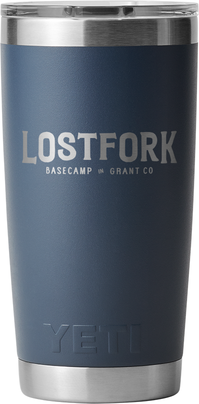 A navy blue insulated tumbler with a stainless steel rim and lid. The tumbler has "LOST FORK BASECAMP in GRANT CO" printed in white and "YETI" embossed near the bottom.