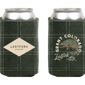 Two dark green plaid can coolers each holding a silver can. One cooler has a diamond-shaped "LOSTFORK BASECAMP" label; the other shows a fish illustration with "GRANT COLORADO Lostfork" text.